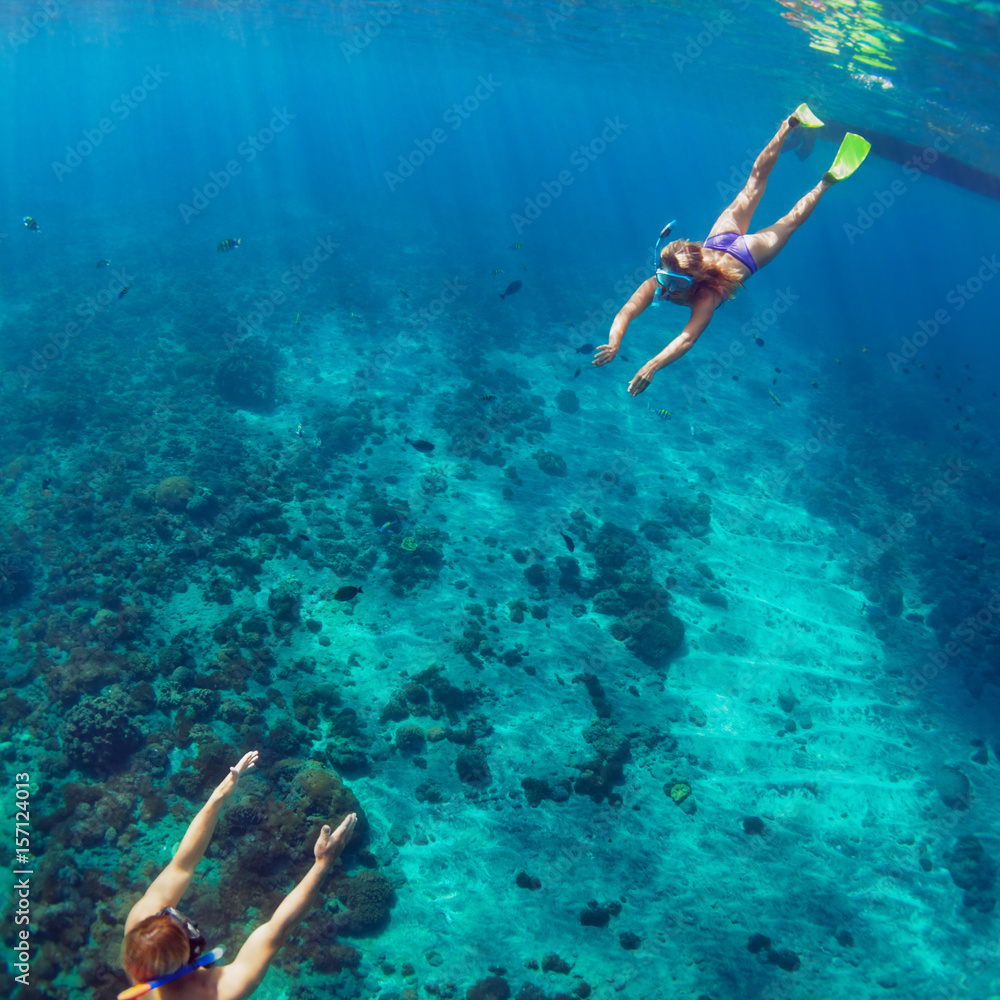 幸福的家庭-戴着浮潜面具的夫妇与热带鱼一起在珊瑚礁深处潜水