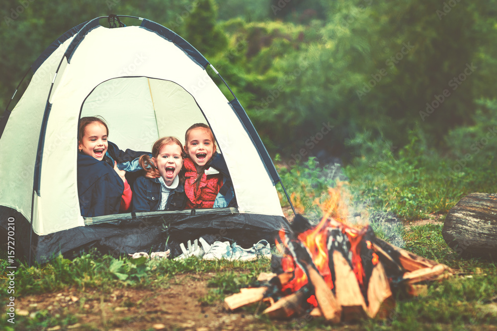 儿童旅游。火灾附近帐篷里的快乐女孩