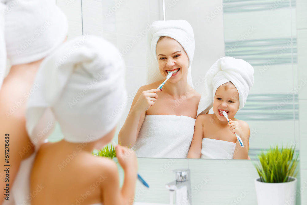 Mother and child daughter brush their teeth with  toothbrush.
