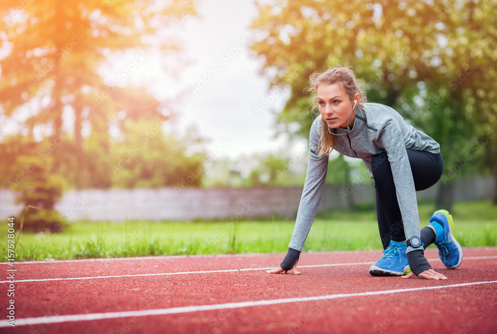 Athletic woman on running track getting ready to start