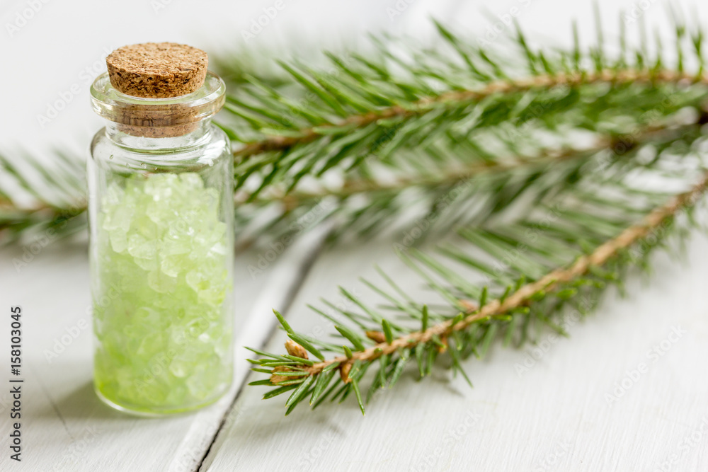 cosmetic spruce salt in bottles with fur branches on white wooden table background