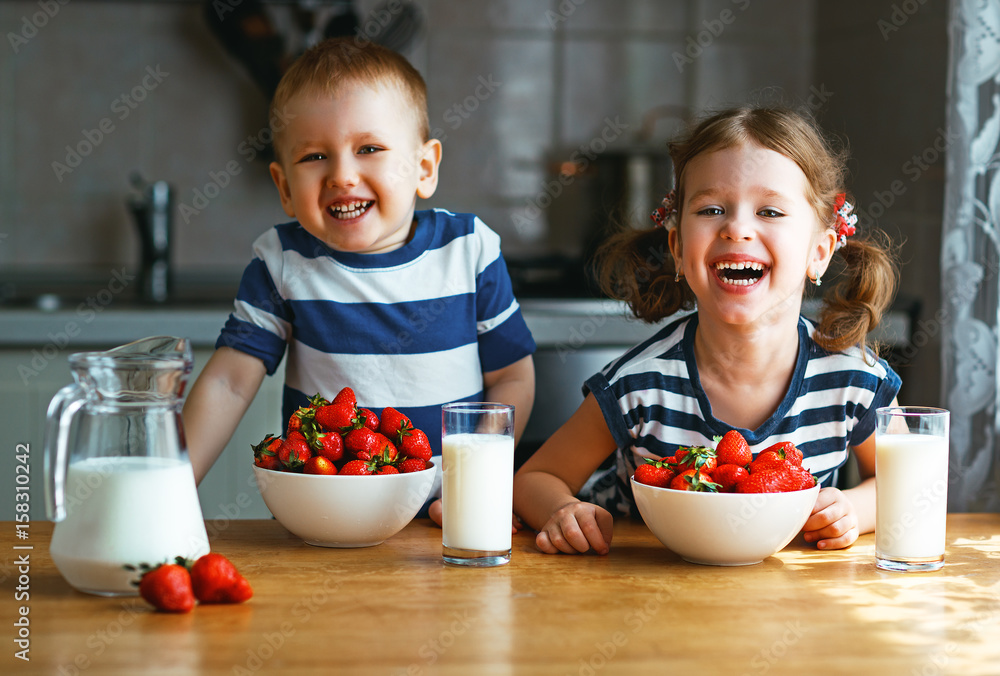 快乐的孩子兄弟姐妹一起吃草莓和牛奶