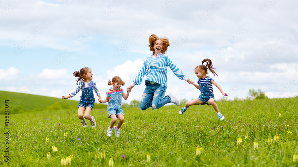 快乐的家庭母亲和孩子女儿女孩在夏天的草地上大笑和跳跃