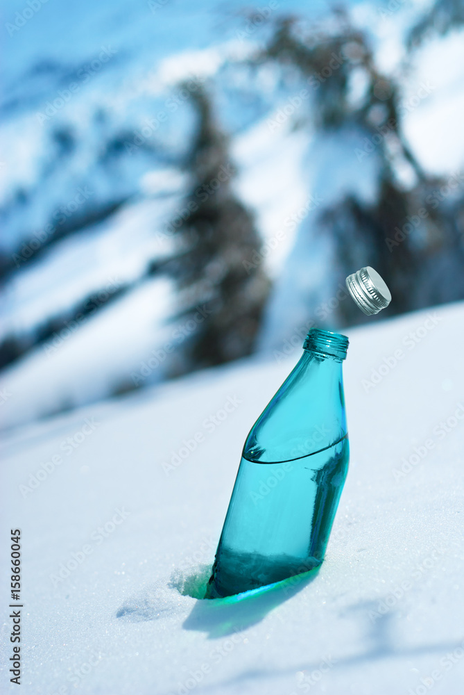 阿尔卑斯山风景背景下的玻璃瓶矿泉水
