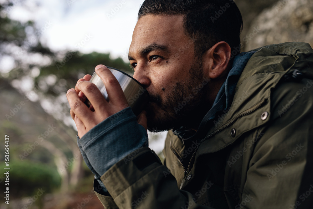 Male hiker taking rest and having coffee outdoors