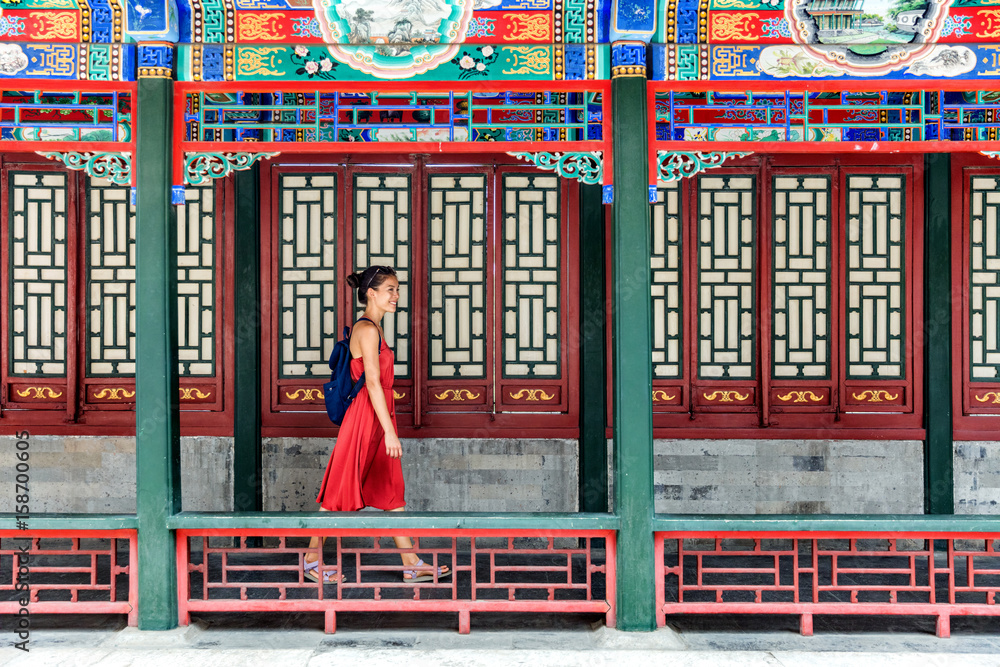 Young backpacker woman walking through old traditional long corridor at chinese temple, china summer