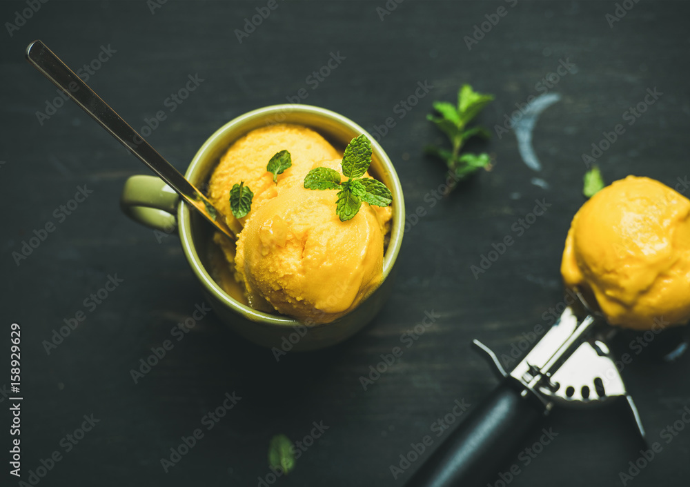 清爽的夏季甜点。芒果冰糕冰淇淋勺，绿色杯子里放着新鲜薄荷，配上黑色的woo