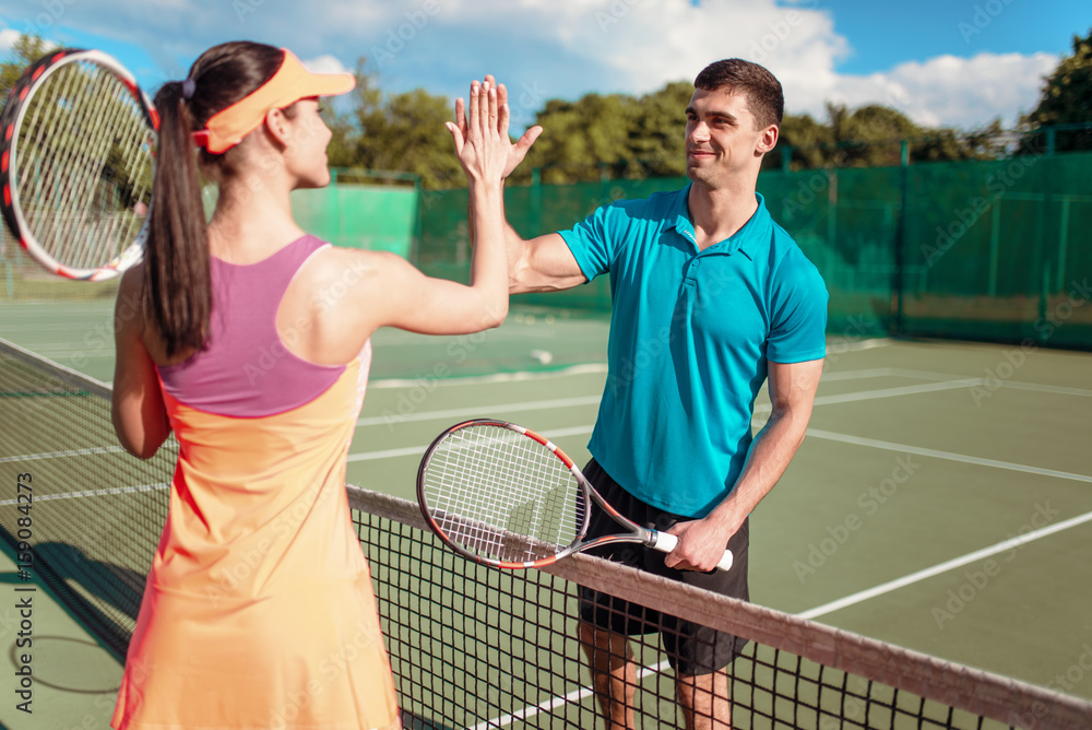 户外网球场上有球拍的幸福情侣