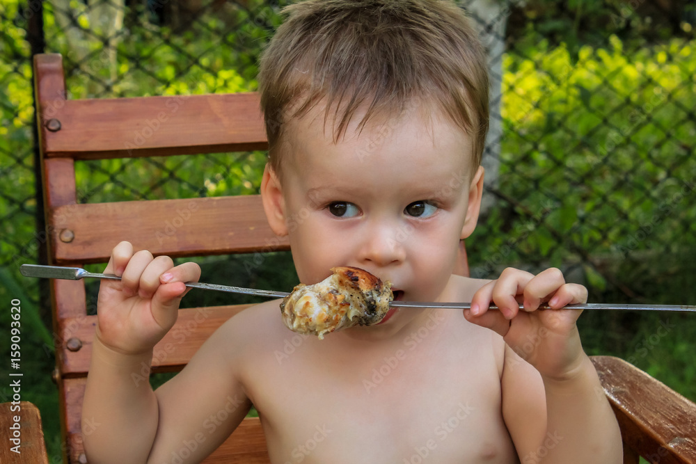 身材魁梧的男孩愉快地吃着烤串。露营。健康的营养和饮食。夏季野餐。