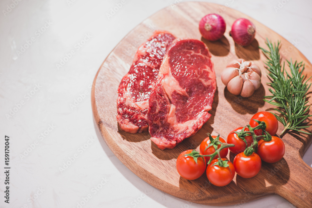 Raw beef on a cutting board  with spices and ingredients for cooking.