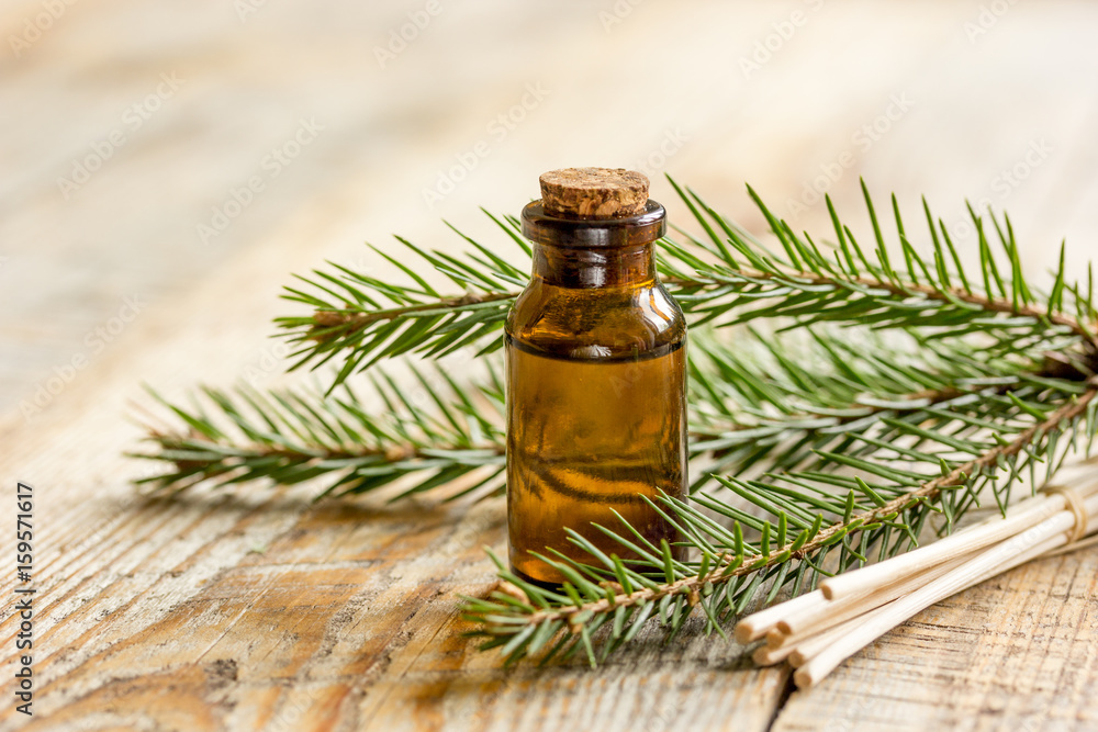 Bottles of essential oil and fir branches for aromatherapy and spa on wooden table background