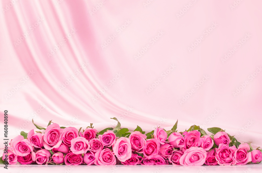 一束甜美的粉红色玫瑰花瓣，柔软的白色丝绸面料，浪漫和爱情卡片的概念