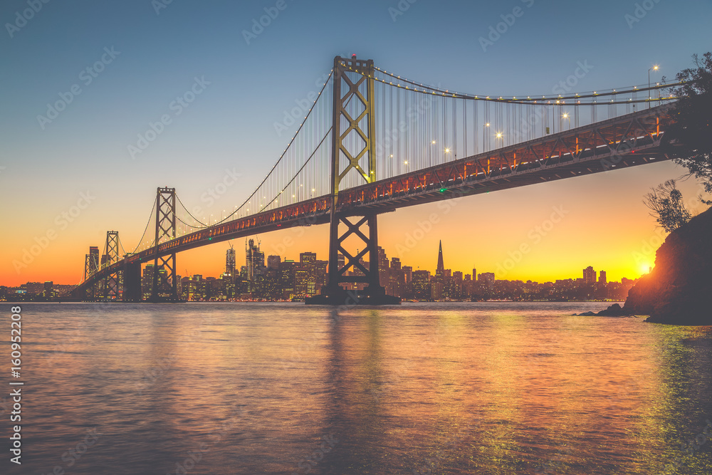 美国加利福尼亚州日落时旧金山奥克兰湾大桥天际线