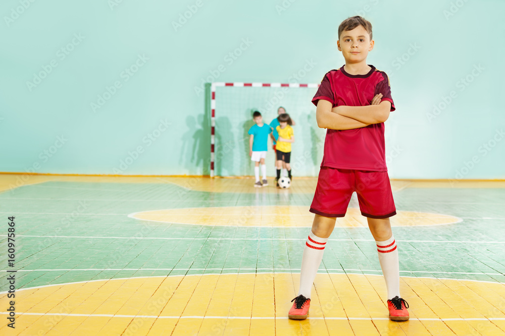 Football player stands confidently in sports hall