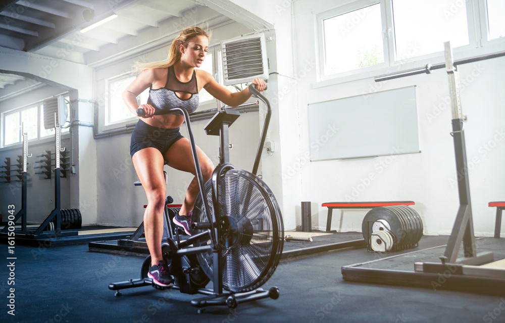 crossfit健身房的女性使用健身自行车进行有氧运动
