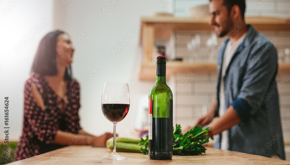 厨房柜台上的葡萄酒，背景是情侣烹饪