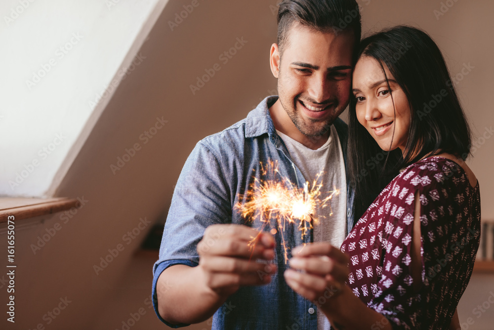 一对恩爱的年轻情侣在家里用焰火庆祝