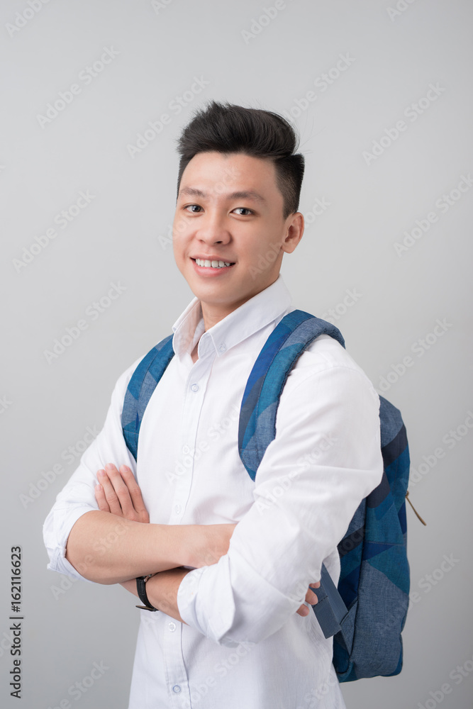 灰色背景下漂亮的亚洲男学生的肖像。