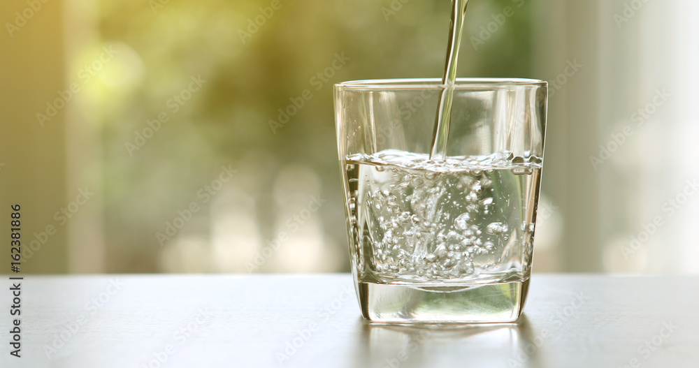 特写从客厅桌子上的瓶子里倒纯净的新鲜饮用水