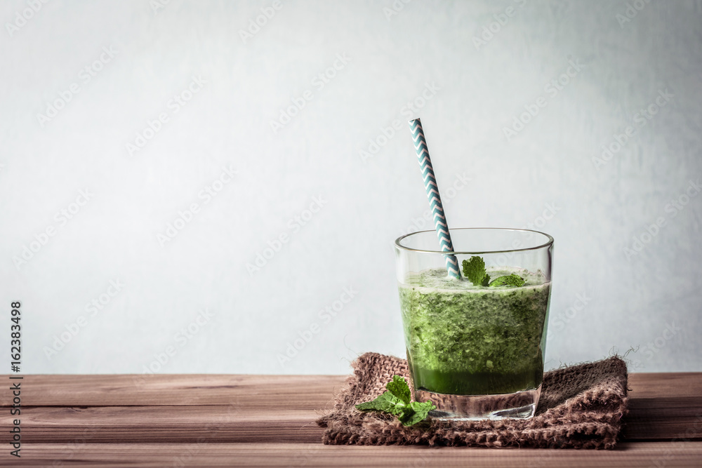 木桌上的饮用杯里有健康的新鲜绿色奶昔汁，可以健康排毒和死亡