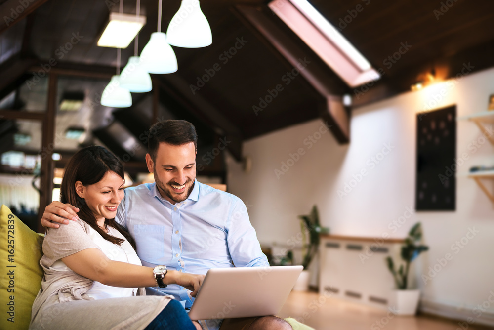 一对年轻夫妇在客厅里拿着笔记本电脑放松身心。