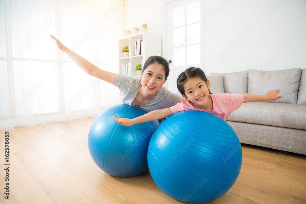 mother and her daughter lying on the ball