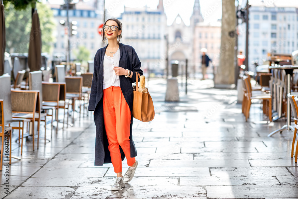 一位法国妇女背着包和法棍走在里昂咖啡馆的街上的生活方式画像