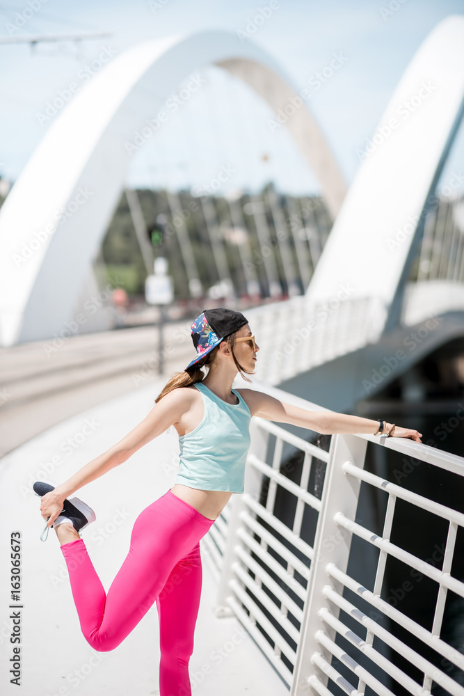 身穿鲜艳运动服的年轻女子在里昂市白色现代桥上户外锻炼