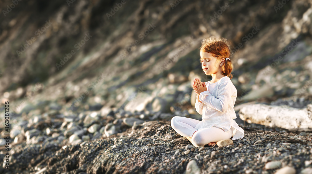 快乐的小女孩以莲花姿势冥想，从事夏季瑜伽