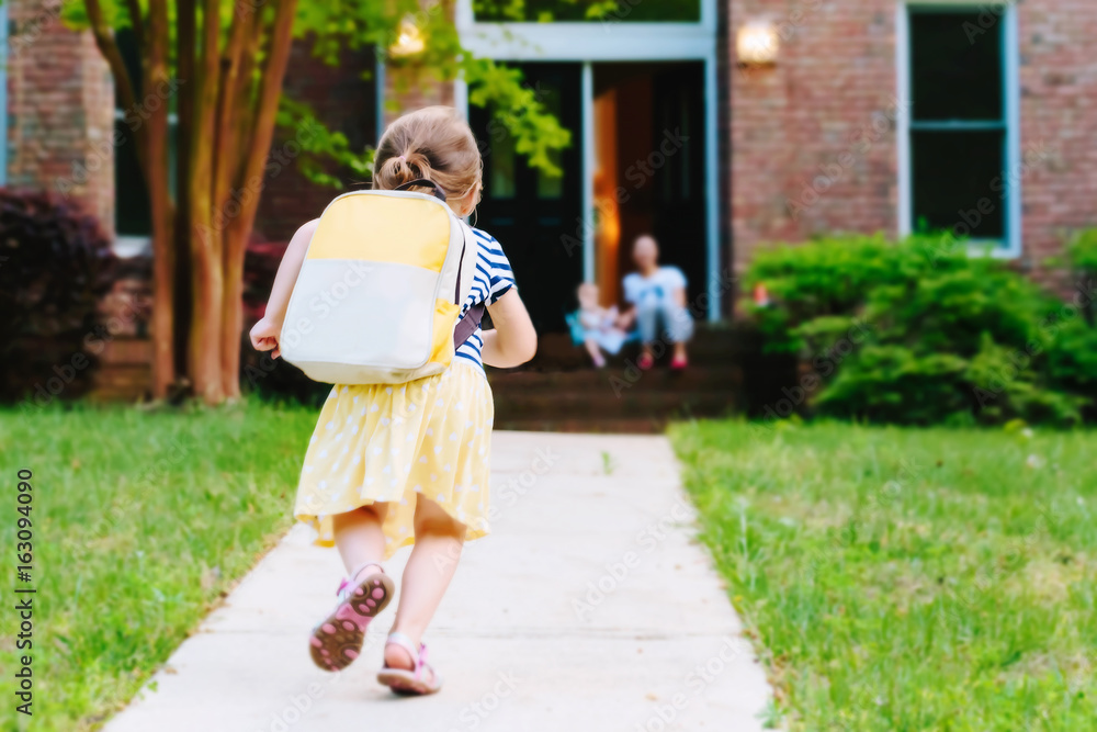快乐的蹒跚学步的女孩背着背包从学校回家