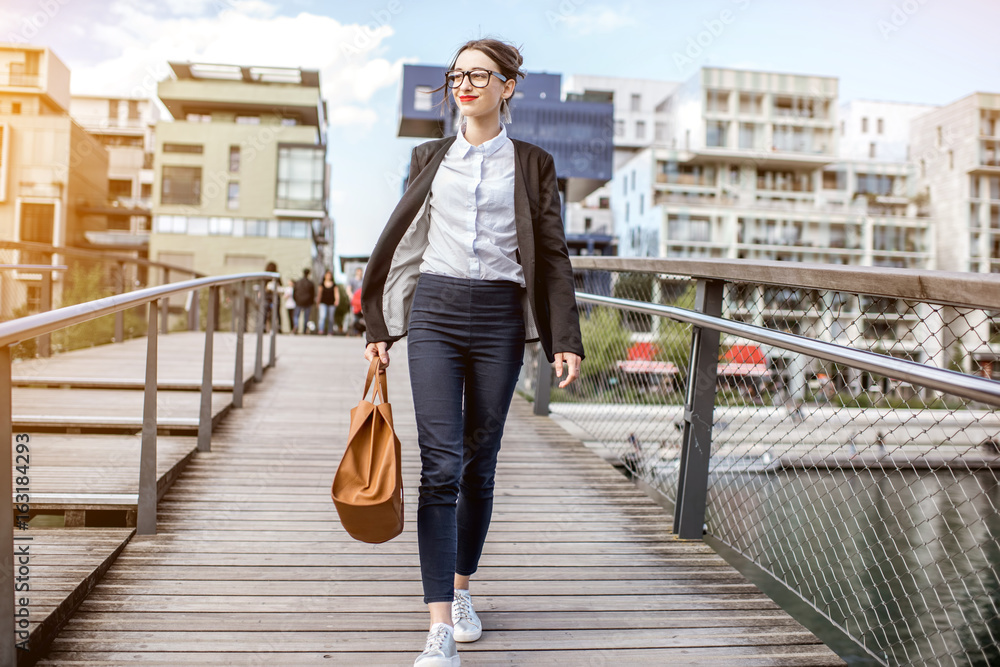 Portrait of a young businesswoman standing on the bridge at the modern residential district in Lyon