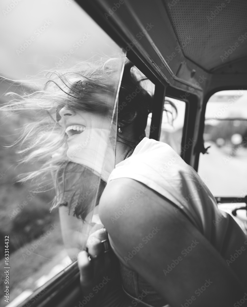 坐在车里的女人把头伸出窗外风吹头发