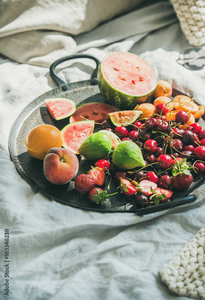 Summer healthy raw vegan clean eating breakfast in bed concept. Tray full of fresh seasonal fruit ov