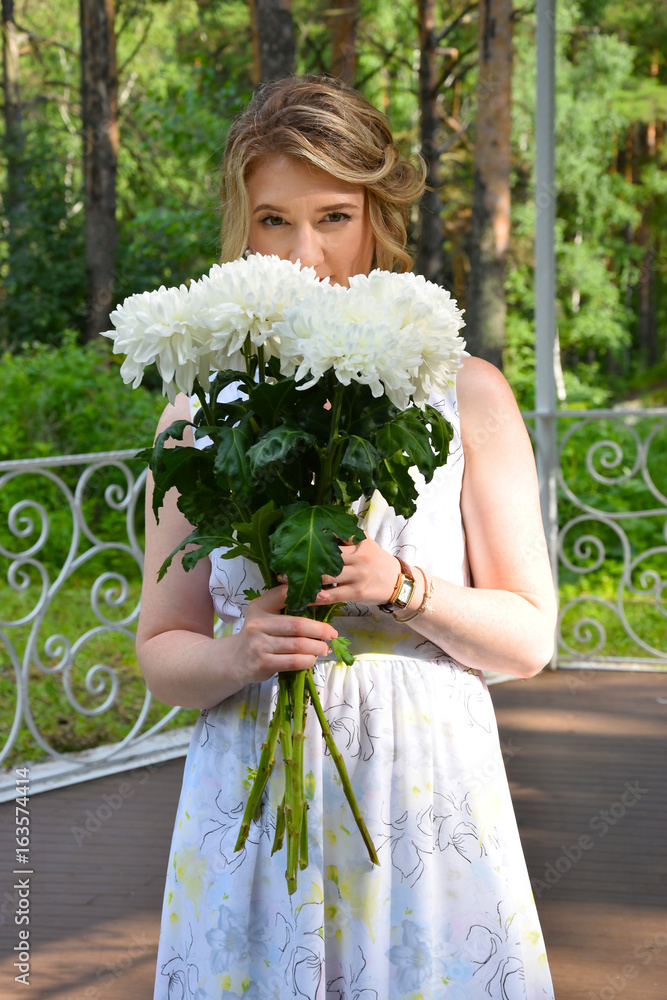 一个快乐的女孩穿着带花的长裙，站在森林的凉亭里。