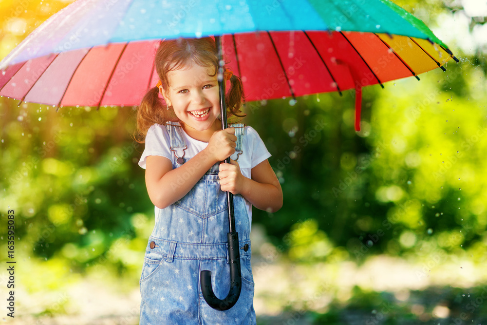 快乐的小女孩撑着伞在夏雨下嬉笑玩耍