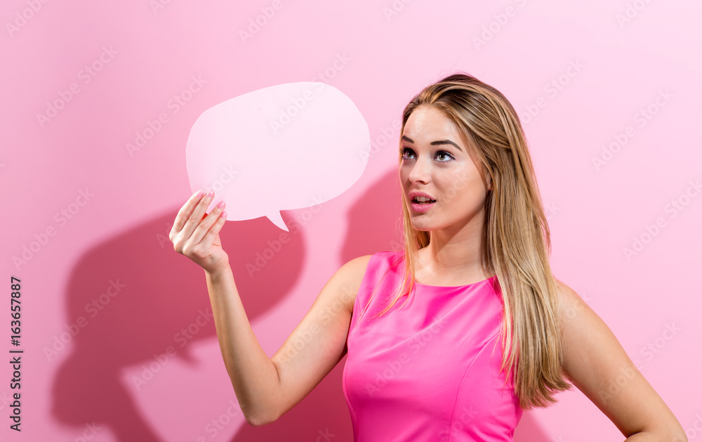 Young woman holding a speech bubble on a pink background