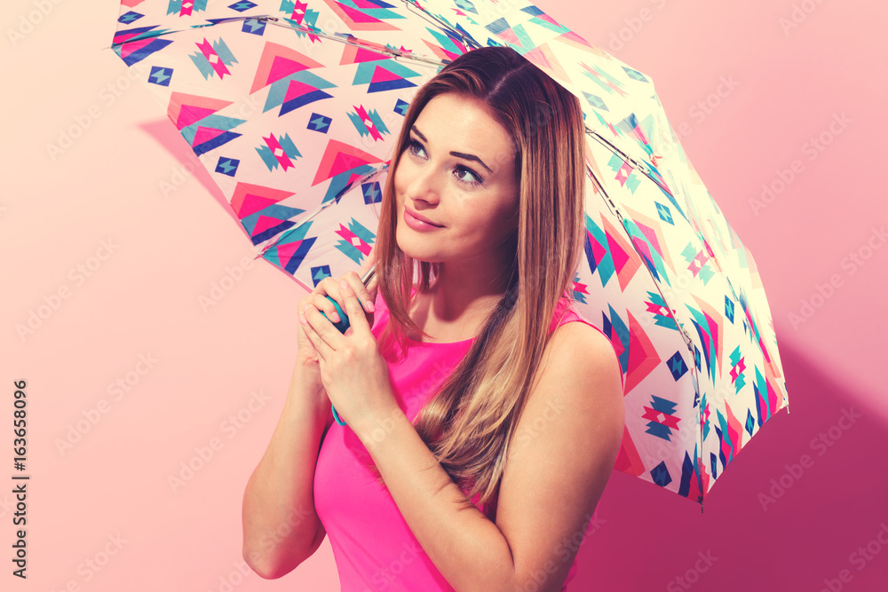 粉色背景下快乐的年轻女子撑着伞