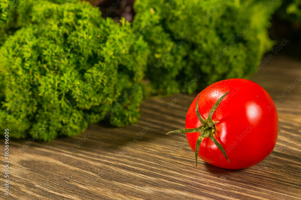 木桌上的多汁成熟番茄，背景是绿色沙拉。新鲜蔬菜。