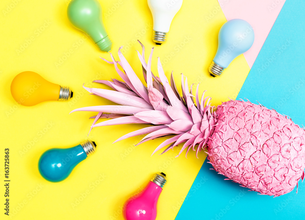 Painted pineapple with light bulbs on bright colored paper background