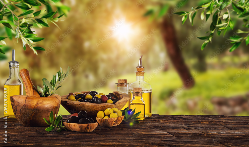 新鲜收获的橄榄浆果装在木碗里，榨油装在玻璃瓶里