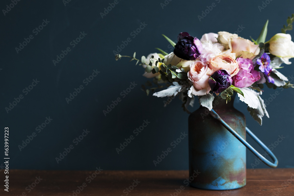 木桌上金属花瓶中的各种鲜花排列