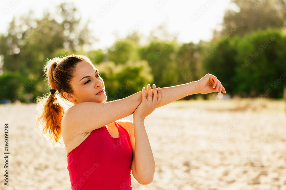 迷人的女人在海滩上跑步后伸展手臂。