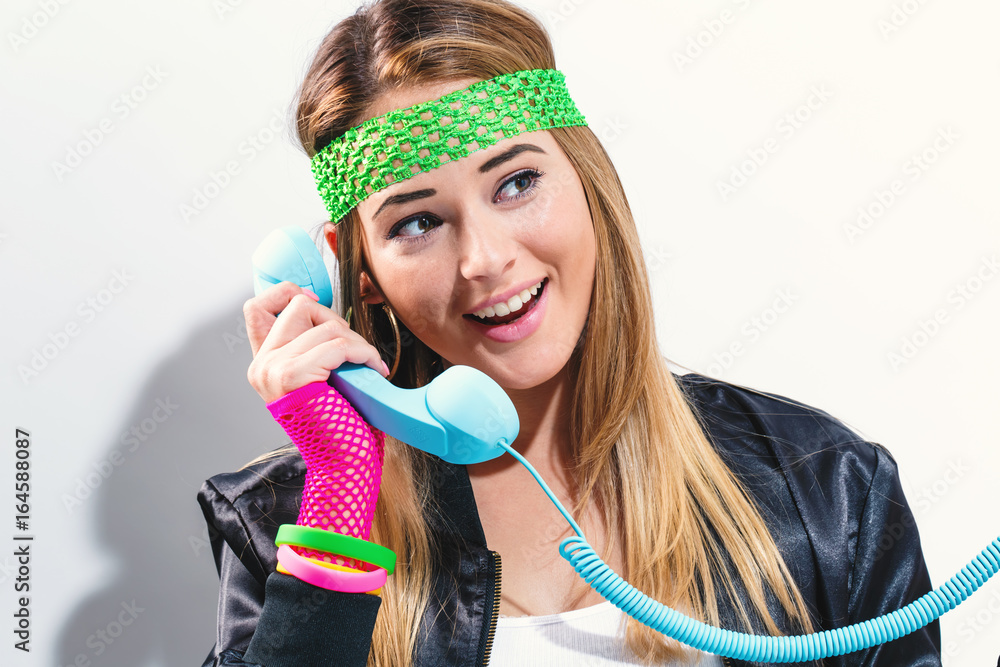 Woman in 1980s fashion with old fashioned phone on a white background