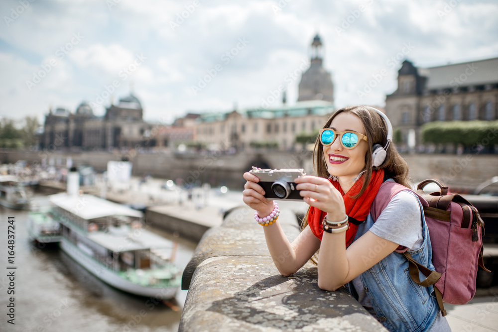 Young woman tourist with photo camera enjoying great view from the bridge on the old town of Dresden