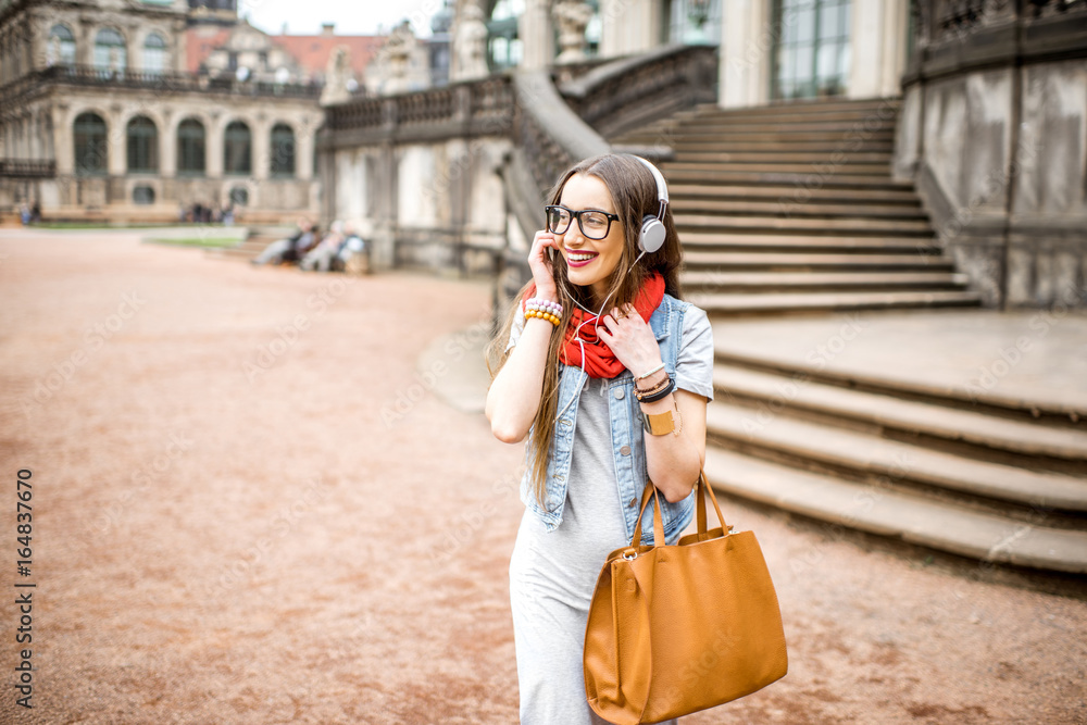 在德国德累斯顿市的老城区，一位戴着耳机和包包行走的时尚女性的肖像