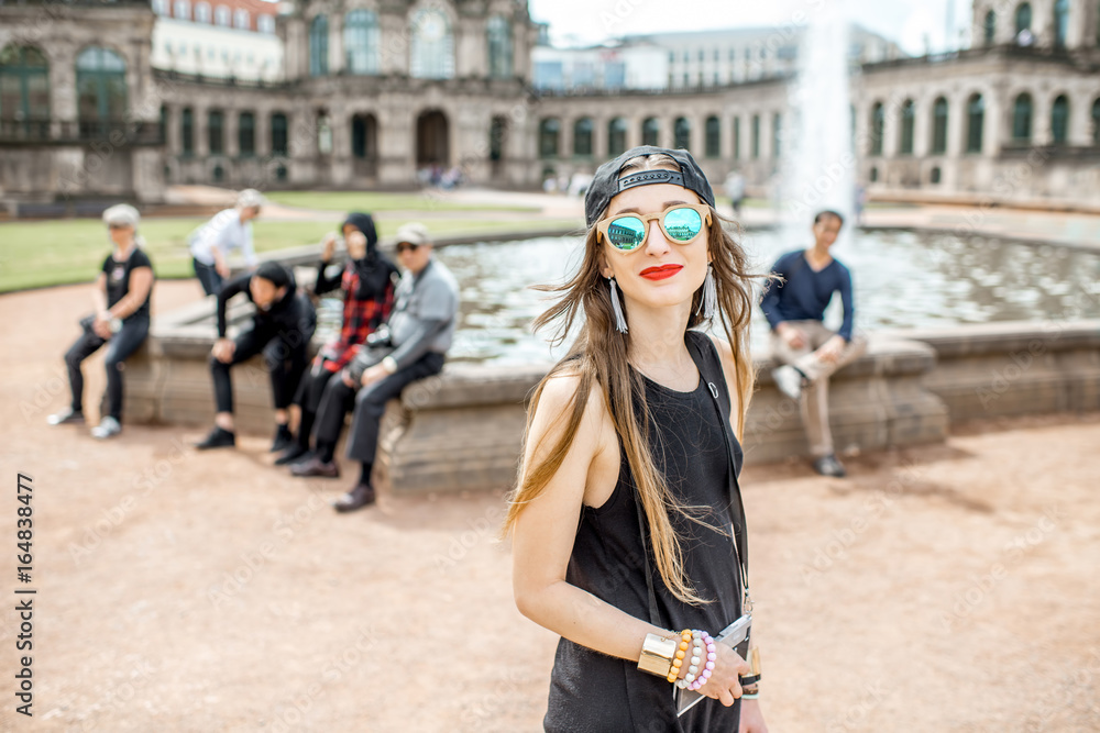 德国德累斯顿老城喷泉附近，年轻的女游客拿着相机行走