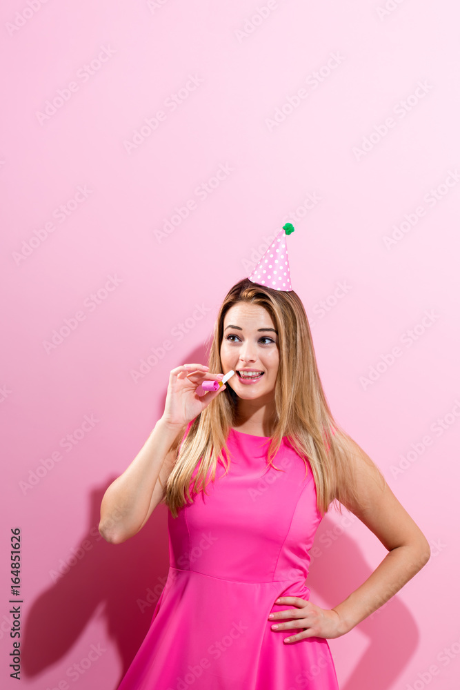 戴着派对帽的年轻女子，带噪音制造器