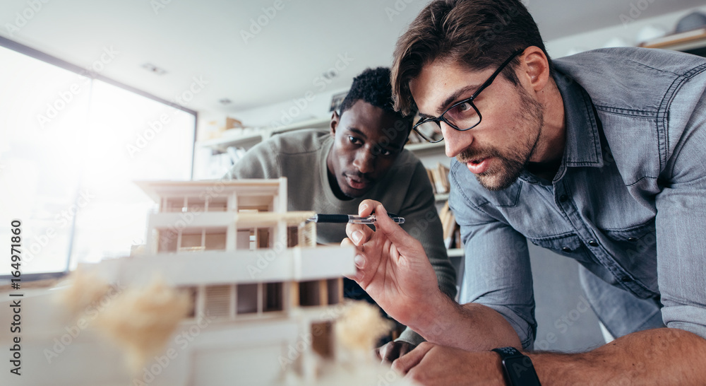 两位男建筑师讨论房屋模型