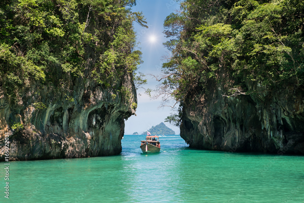 泰国普吉岛美丽的岩石山和清澈的海水景观，配有长尾船。