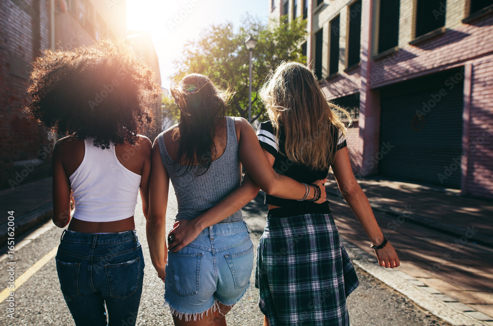 三个年轻女人一起走在城市街道上